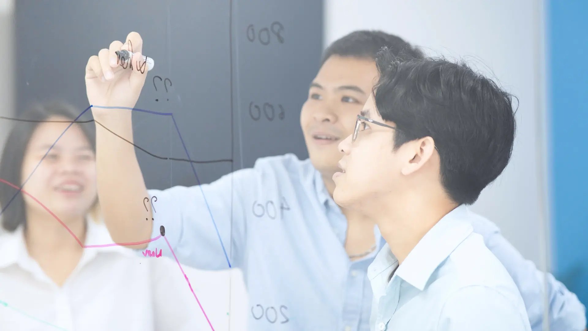 - Seven Peaks team collaborating on data trends drawn on a glass board.